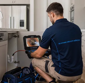 Plumber clearing a blocked toilet in a Surry Hills bathroom